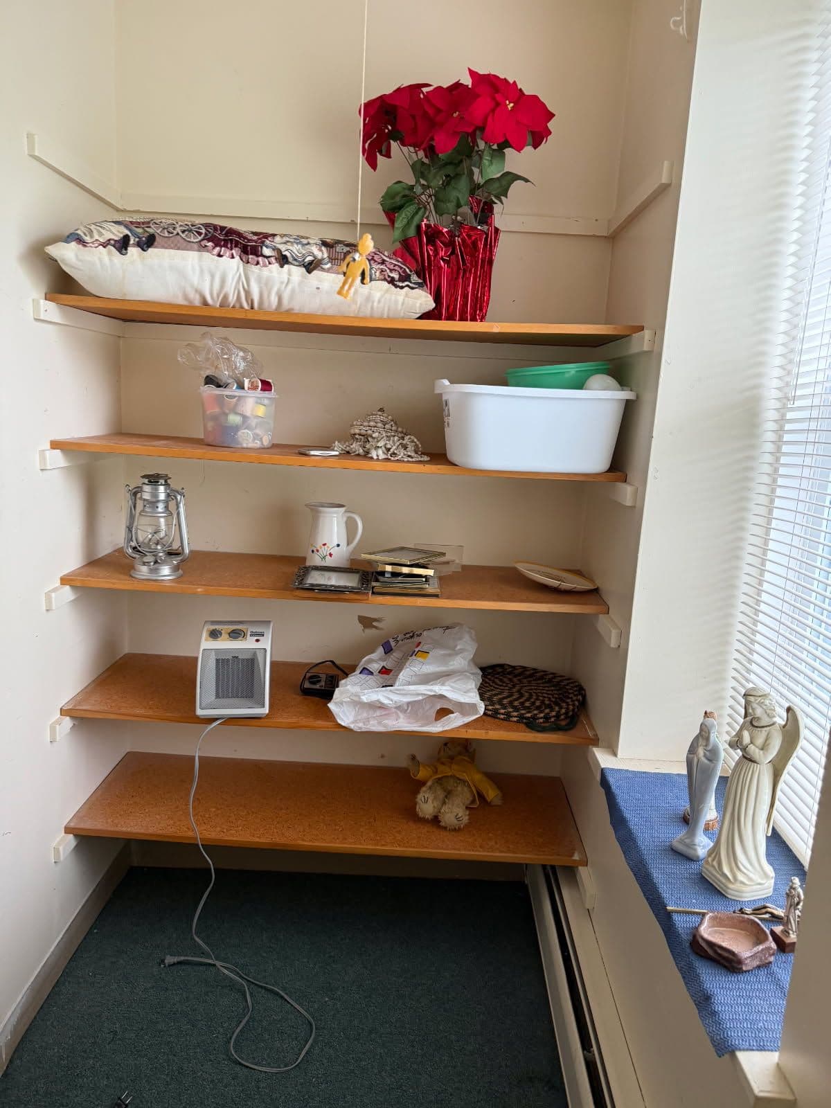 Organized shelf with holiday flowers, assorted items, and decorative figurines.